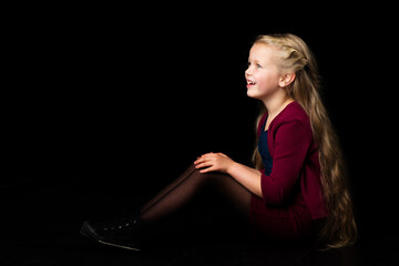 Side view of happy smiling blonde girl. Isolated on black background.