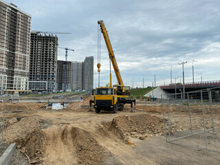 Large yellow mobility modern industrial construction crane mounted on a truck is used in the construction of new housing, houses, buildings in a big city
