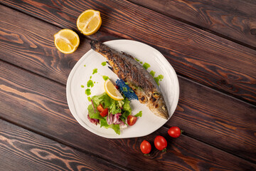 Hot dish seabass fish on charcoal with vegetables on a plate