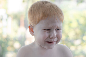 The little red-haired boy is crying. A 4 year old boy is lost in the park and is crying.
