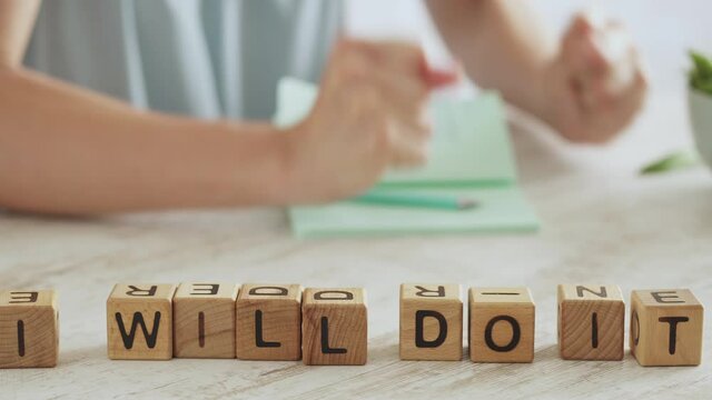 Motivational message on table NEVER GIVE UP. Joyful contented woman makes positive gesture, clenches her fists. Motivation to achieve results. Concepts for success and self-confidence. I can and will
