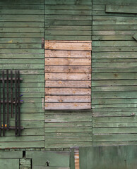 wooden green wall with boarded up window.