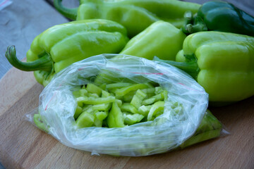 A bag of bell peppers, cut into strips for freezing. Fresh vegetables in a package lie on a wooden background.