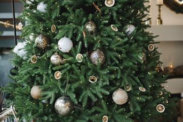 Christmas tree with baubles and fairy lights. Christmas background. Close up of Christmas ornaments on tree. Christmas tree in white and gold color