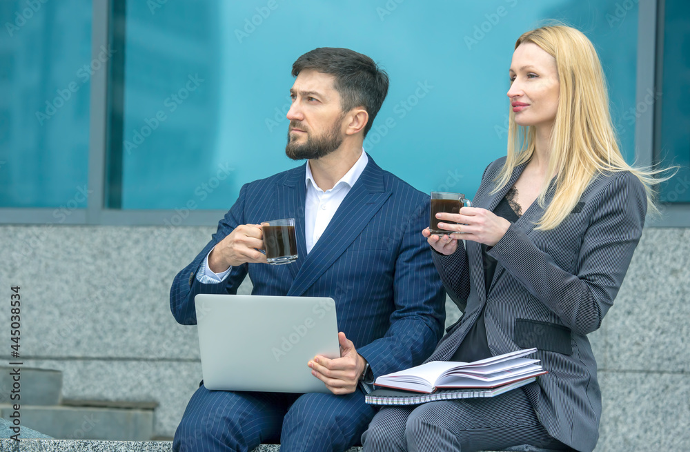 Wall mural businessmen partners man and woman on a city street discuss a business project and drink coffee