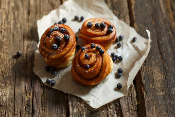 Bun with blueberries on a dark table, rustic style. Baking with berries
