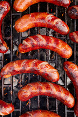 Grilled sausages on a cast iron grill, top view. BBQ sausage