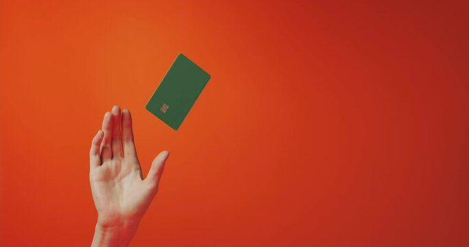 Female hand and levitating template mockup bank credit card isolated on orange background, copy space