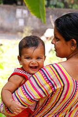 mother holding an indian cute baby boy with smile