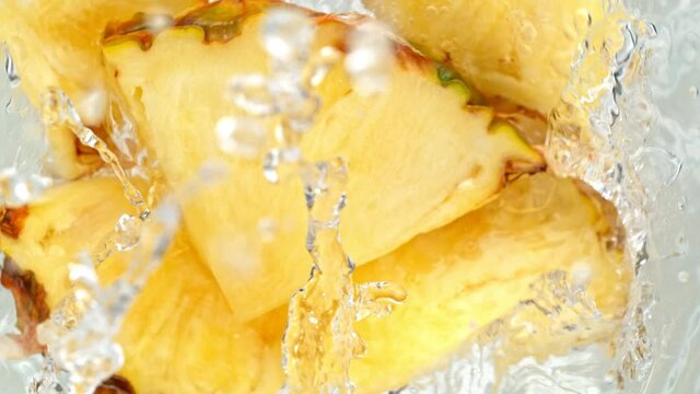 Super Slow Motion Shot of Pineapple Slices Falling Into Water Whirl at 1000 fps.