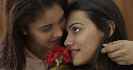 Young gorgeous South Asian ladies from India being affectionate holding a flower
