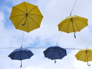 Vor blauem Himmel aufgespannte gelbe und blaue Regenschirme