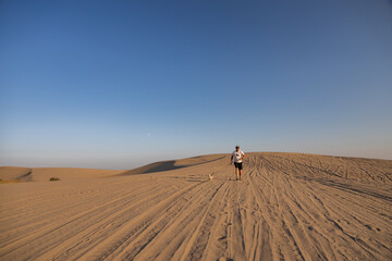 Man with small brown dog running on St. Anthony sand dunes, Idaho, USA