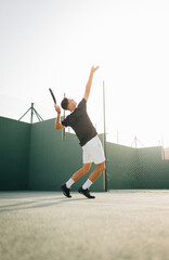 Man playing paddle tennis on an outdoor green paddle tennis court behind the net