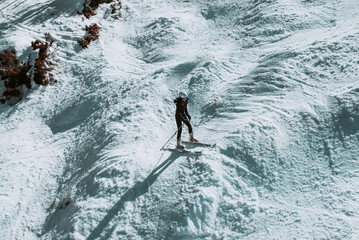 People in winter enjoying the snowy mountains where are practised plenty of activities such as skiing and snowboarding with a clear sky and some clouds on the horizon.