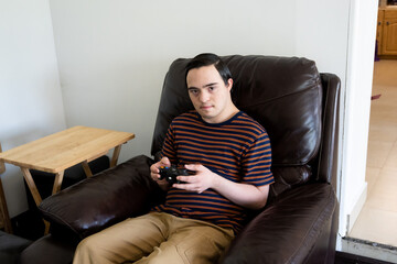 young adult with down syndrome playing video games in couch