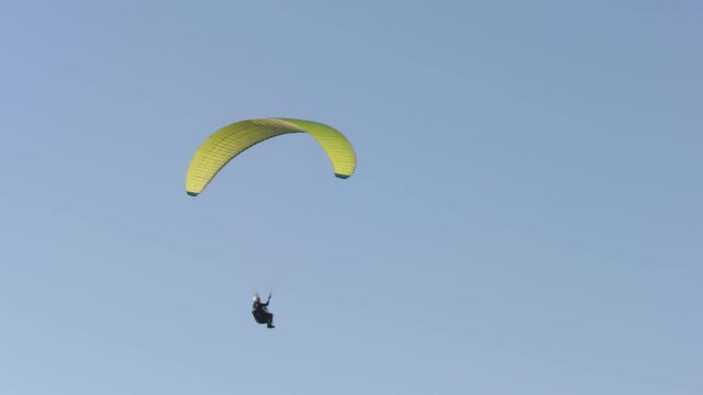 Paraglider flies against the background of a blue sky. 