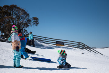 People in winter enjoying the snowy mountains where are practised plenty of activities such as skiing and snowboarding with a clear sky and some clouds on the horizon.