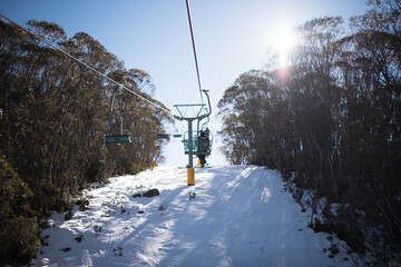 People in winter enjoying the snowy mountains where are practised plenty of activities such as skiing and snowboarding with a clear sky and some clouds on the horizon.