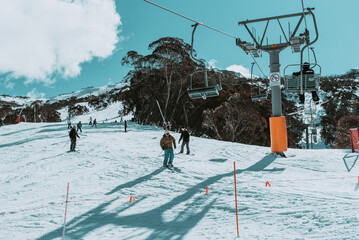 People in winter enjoying the snowy mountains where are practised plenty of activities such as skiing and snowboarding with a clear sky and some clouds on the horizon.