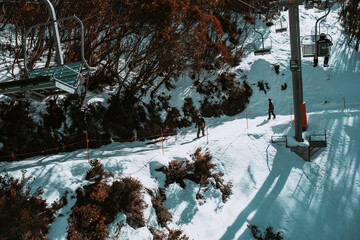People in winter enjoying the snowy mountains where are practised plenty of activities such as skiing and snowboarding with a clear sky and some clouds on the horizon.