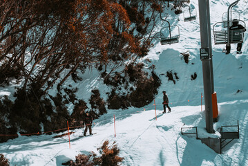 People in winter enjoying the snowy mountains where are practised plenty of activities such as skiing and snowboarding with a clear sky and some clouds on the horizon.