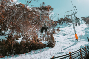 People in winter enjoying the snowy mountains where are practised plenty of activities such as skiing and snowboarding with a clear sky and some clouds on the horizon.