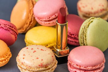 Macarons on dark background, colourful french cookies macarons and red classical lipstick 