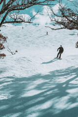People in winter enjoying the snowy mountains where are practised plenty of activities such as skiing and snowboarding with a clear sky and some clouds on the horizon.