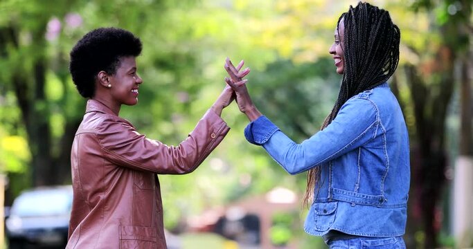 Two African women joining hands together outside