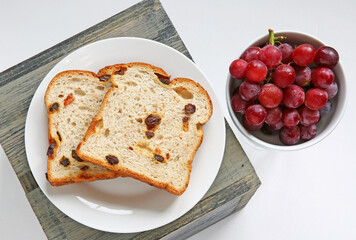 sliced raisin bread and grapes together against white background