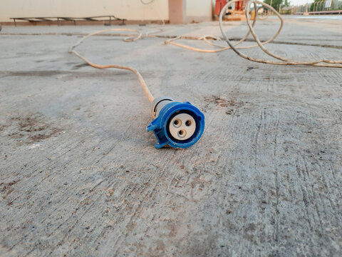 electric socket with a three-pin model and not in use and placed on a concrete floor