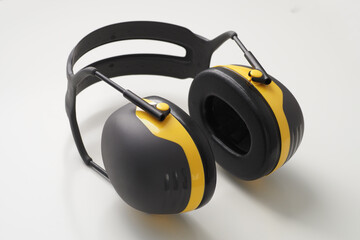 Yellow ear muffs on white desk. Protective headphones. - obrazy, fototapety, plakaty
