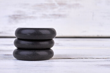 Stack of spa hot stones on white wooden background.