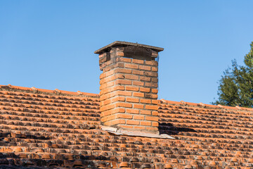 Roof with tiles and red chimney in the interior of Brazil. In the background trees and blue sky.