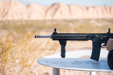 Black ar and rifle aiming on the left side with a blurry background of a desert