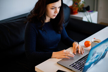 The girl works on the computer and drinks tea with lemon