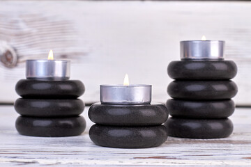 Stacks of black stones and burning candles still life.