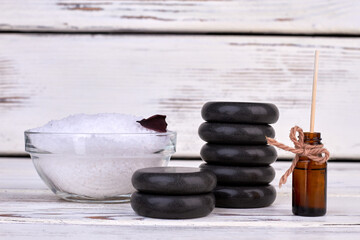 Pile of bath salt with stones and oil bottle on white background.