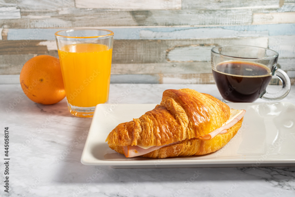 Poster crunchy delicious croissant with ham and cheese filling, a cup of hot coffee and juice on a table