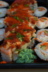 sushi rolls with salmon, shrimp,cucumbers are decorated with caviar (tobiko) with wasabi. close-up