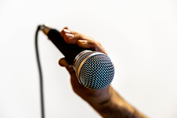 Man's hand holding a microphone with a white background