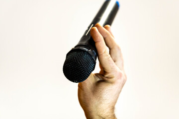 Man's hand holding a microphone with a white background