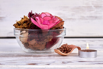 Glass bowl with many different flowers and burning candle.