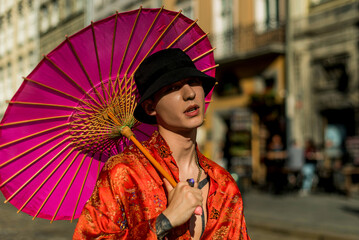 Positive man portrait with dressed in street style clothes red kimono with chains around neck with pink umbrella. Youth and lifestyle concept. Luxury rap artist. - obrazy, fototapety, plakaty
