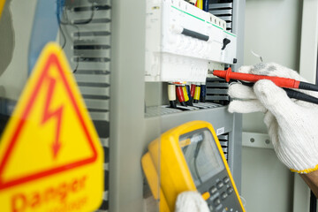 Electrician measurements with multimeter testing electrical installations and wiring on protective current electric in control panel.