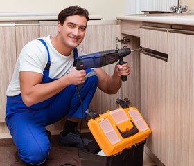 Young repairman working at the kitchen