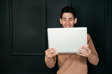 Young happy student with laptop and phone.