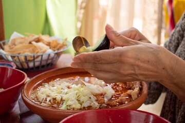 Woman eating a dish of pozole 