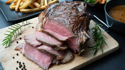 Close-up view of Grilled marble Rib eye steak beef for steak on wooden plate with salad and French fries.